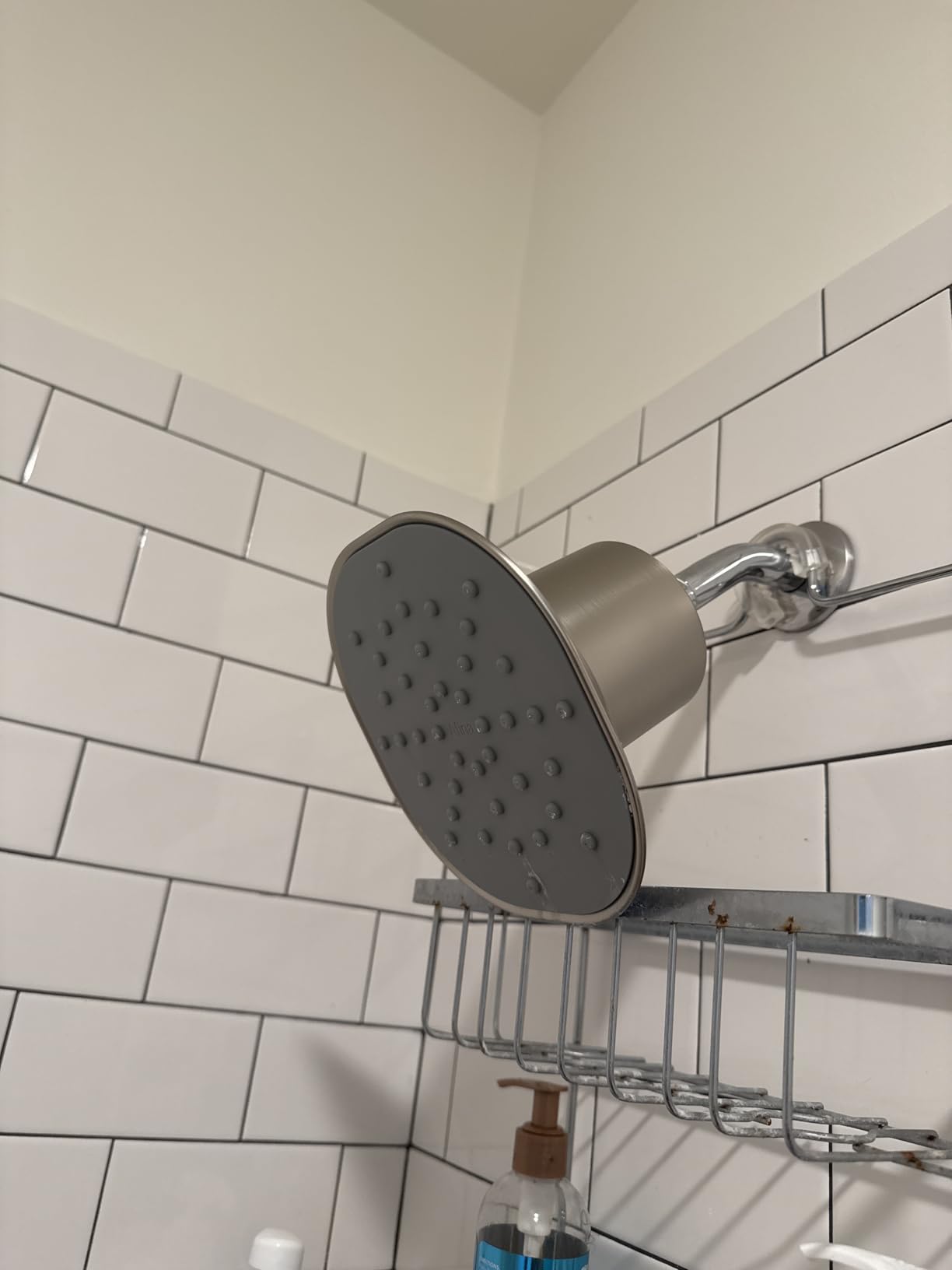 Afina shower head installed in a modern white-tiled bathroom, showing its clean design and compact fit.