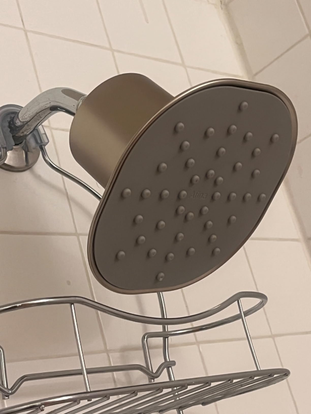 Afina shower head mounted in a tiled shower above a metal shelf, showing easy home installation setup.